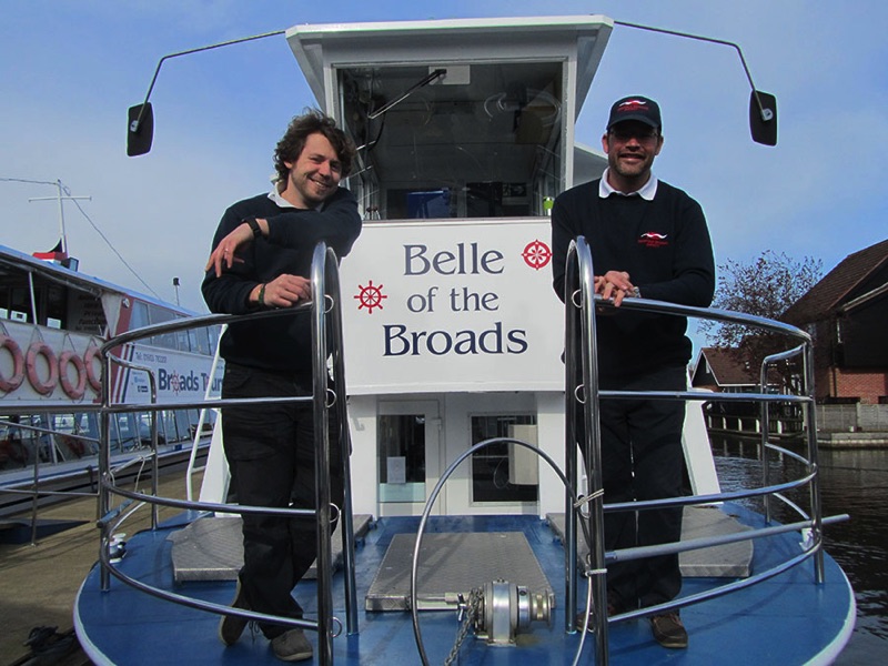 two men standing at the front of belle of the broads passenger trip boat